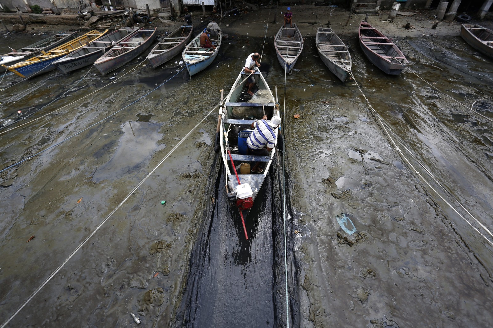 Pescadores e barcos em área assoreada